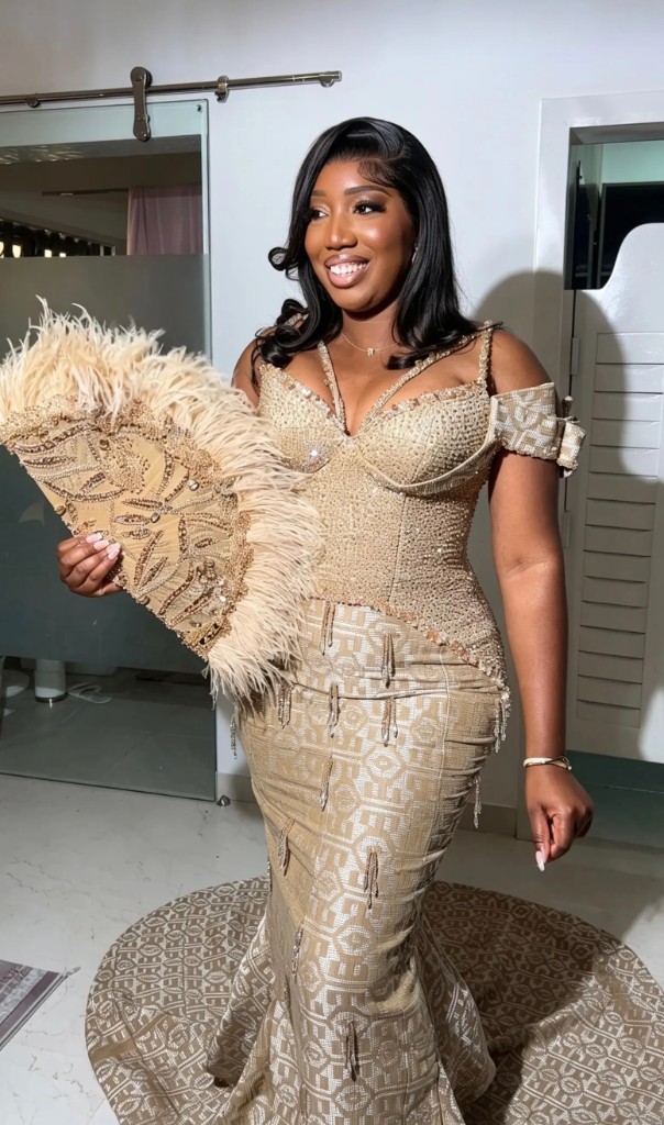 Bridal client in an embellished gold gown with feathered fan
